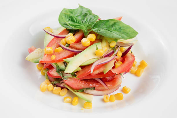istock Vegetable salad with avocado, tomatoes and corn on white plate. Close-up 995493240