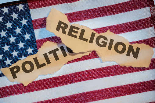 Old torn paper with the words Religion on top of the word Politics with American Flag