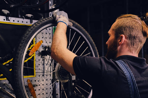istock Mechanic repairing bicycle wheel tire in a workshop. 995517184