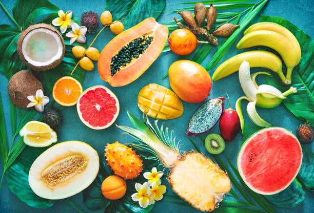 Assortment of tropical fruits with palm leaves and exotic flowers Assortment of tropical fruits with palm leaves and exotic flowers. Top view dragon fruit flower stock pictures, royalty-free photos & images