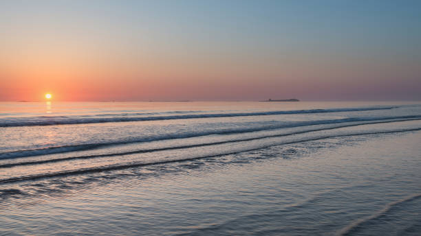 bella alba vibrante colorata sulla scena tranquilla del paesaggio della spiaggia di bassa marea - bamburgh northumberland england beach cloud foto e immagini stock