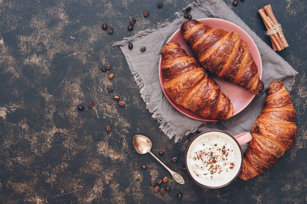 istock Croissants with coffee on a dark surface, top view, copy space. 995524364