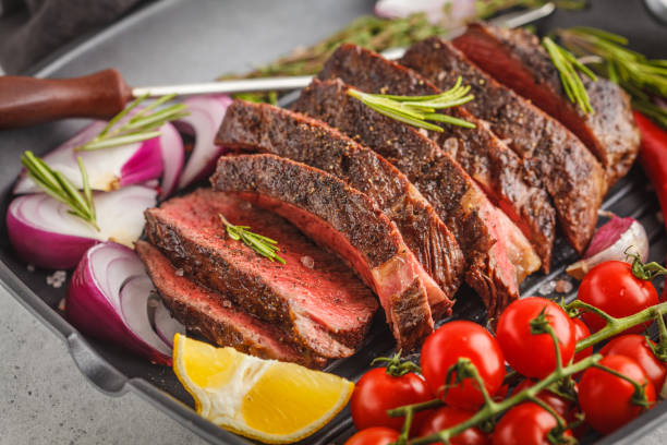 istock Sliced roast beef in a frying pan with spices and vegetables, white background, macro 995533804