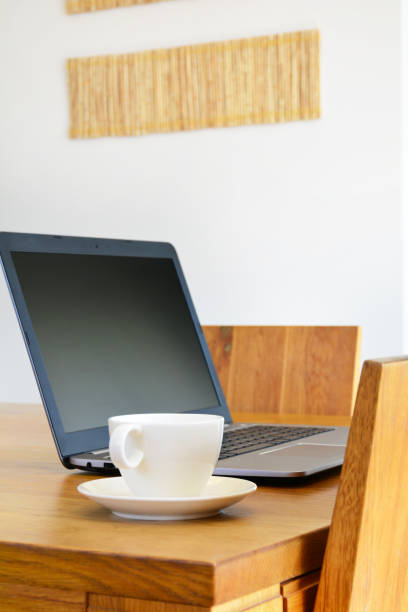 istock White ceramic cup and laptop on oak wood dining table 995534530