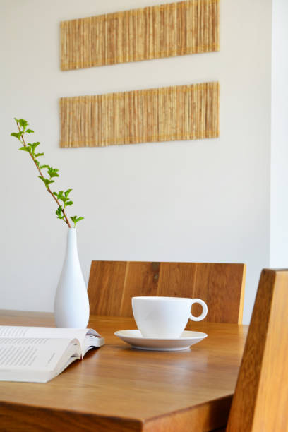 istock White ceramic cup, open book and vase on oak wood dining table 995534552