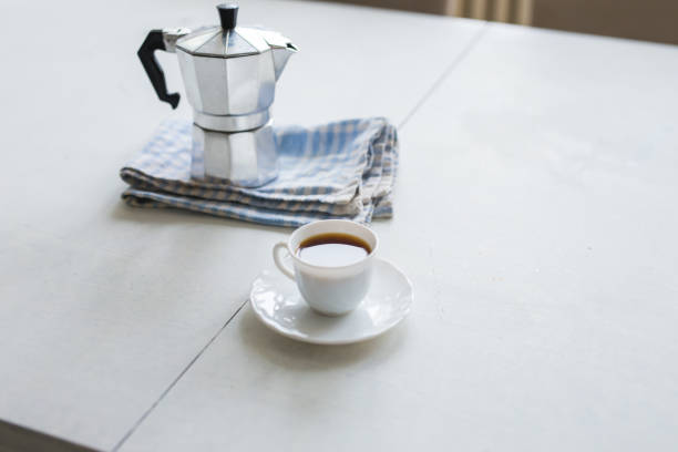 istock Cup of coffee, coffee kettle on a white table 995539784