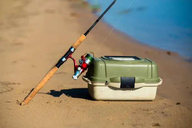 Photo of Spinning and fishing box on riverside close-up view