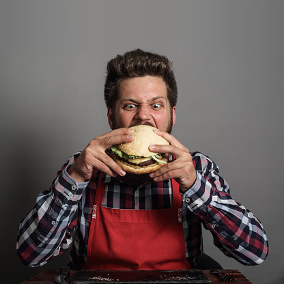 Young man biting fresh tasty hamburger