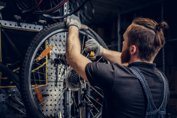 istock Mechanic repairing bicycle wheel tire in a workshop. 995563022