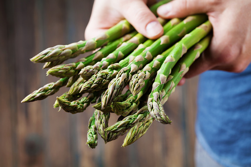 Farmer holding in hands the harvest of fresh green asparagus. Organic and diet vegetables.