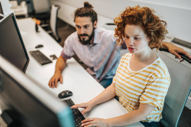 istock Redhead female programmer and her colleague working on desktop PC in the office. 995583988