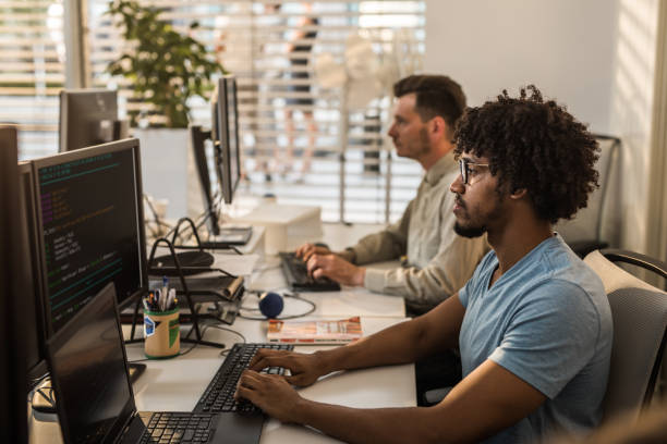 istock Profile view of concentrated software designer working on desktop PC in the office. 995595978