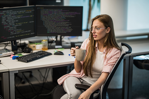 Young woman resting on a coffee break while working in computer programming company.