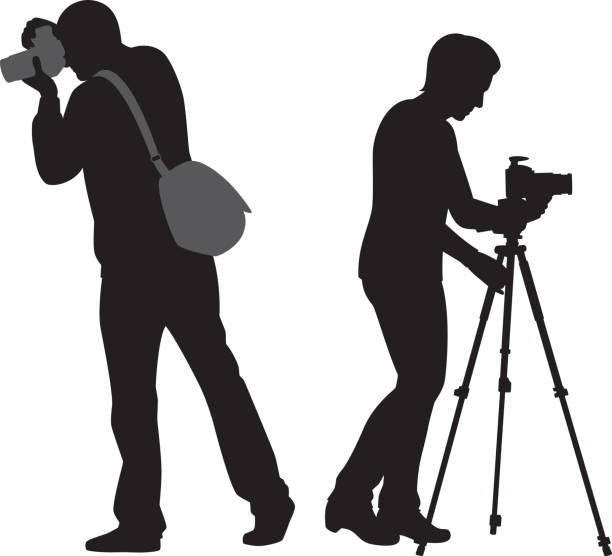 istock Man and Woman with Cameras and Tripod Silhouette 995608578
