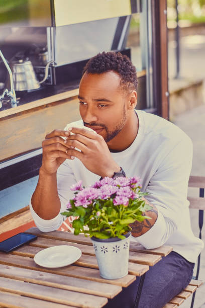 istock Black male drinks coffee and using smartphone. 995612346