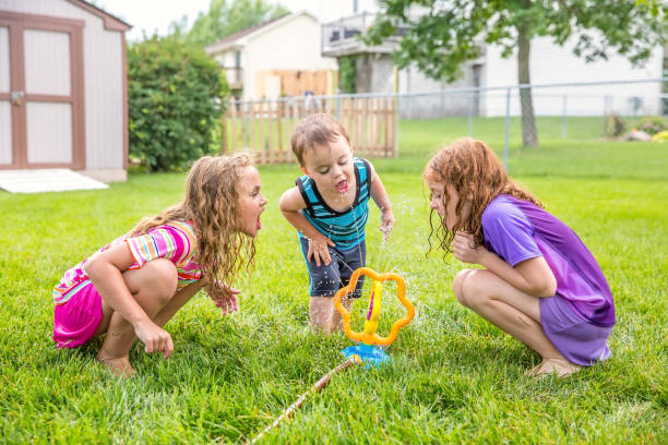 istock Three Children Drinking Water From Sprinkler in Back Yard 995613406