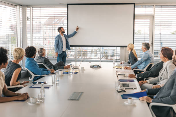 CEO giving a business presentation through projection screen in a board room.