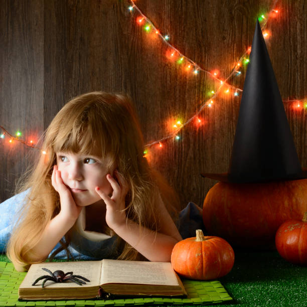kleines mädchen in ein buch über kürbisse hexenhut - halloween witchs hat witch autumn stock-fotos und bilder