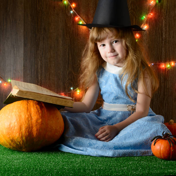 kleines mädchen in ein buch über kürbisse hexenhut - halloween witchs hat witch autumn stock-fotos und bilder