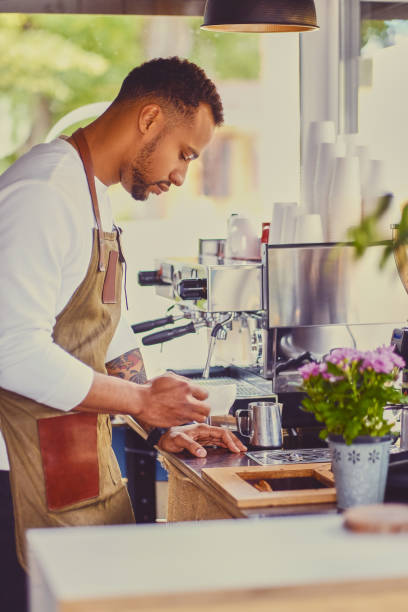 istock Black bearded coffee seller pouring coffee. 995617140