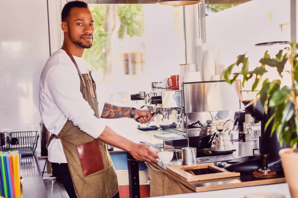 istock Black bearded coffee seller pouring coffee. 995633336