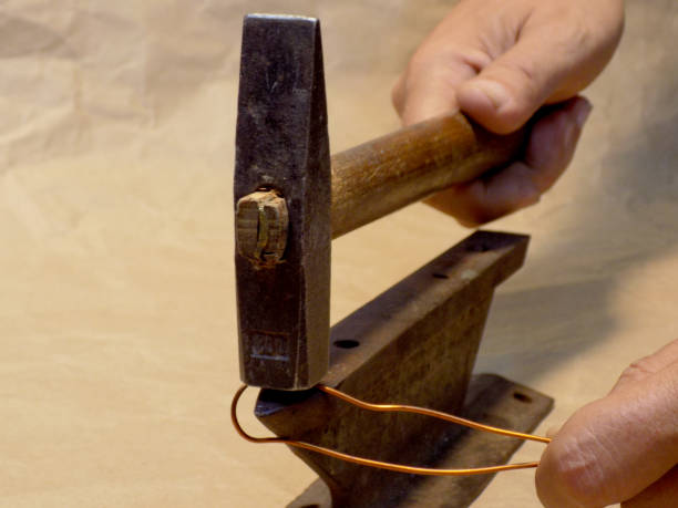 istock The workman corrects the wire with an iron hammer on an anvil 995651794