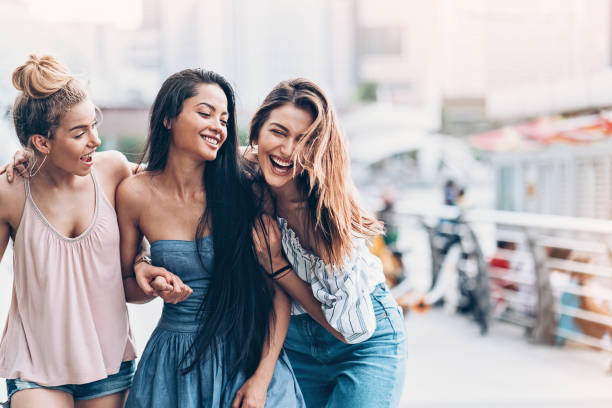 Three young women walking and laughing Group of happy girls walking outdoors singapore photos stock pictures, royalty-free photos & images