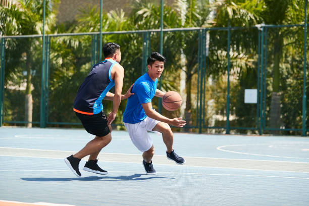 adulto joven asiática jugando baloncesto uno-a-uno - basketball sport basketball player athlete fotografías e imágenes de stock