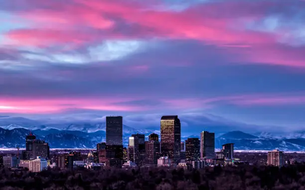 Photography of the Denver Skyline at Sunset with snowy winter peaks in distance.