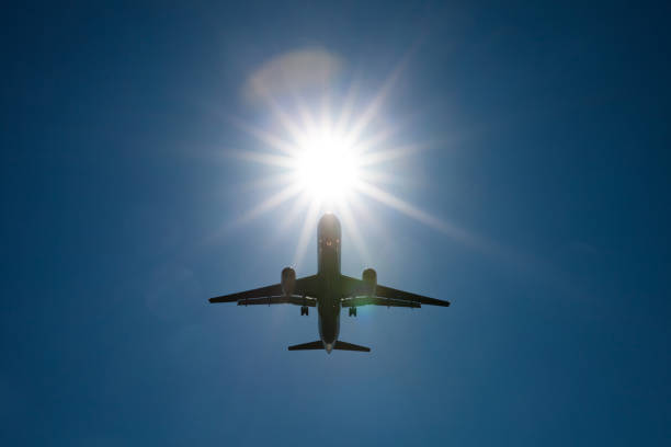 istock Silhouette passenger airplane against bright sun 995733386