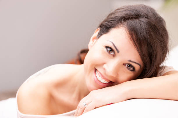 istock beautiful coy woman smiling on her sofa 995735868