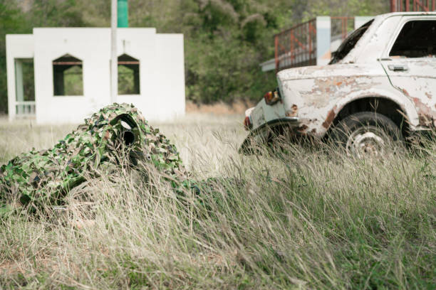 snajper żołnierz leżący na ziemi i kamuflaż w trawie. żołnierz trzymający broń i waring armor uniform. wojsko jest odpowiedzialne za utrzymanie terytorium. - cloaking zdjęcia i obrazy z banku zdjęć