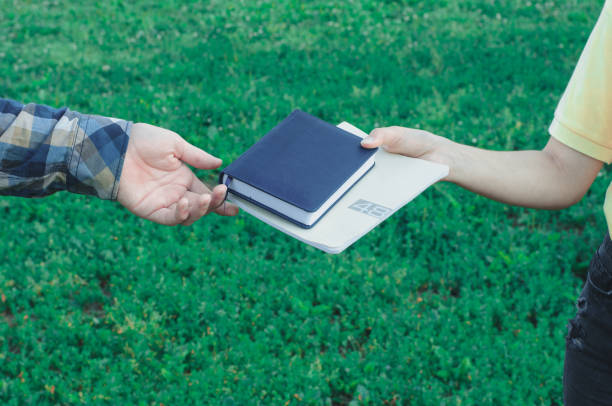 Boy returning books to girl outdoors near college stock photo