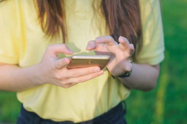 Teenager touching a screen. Woman holding a mobile phone in hands. stock photo