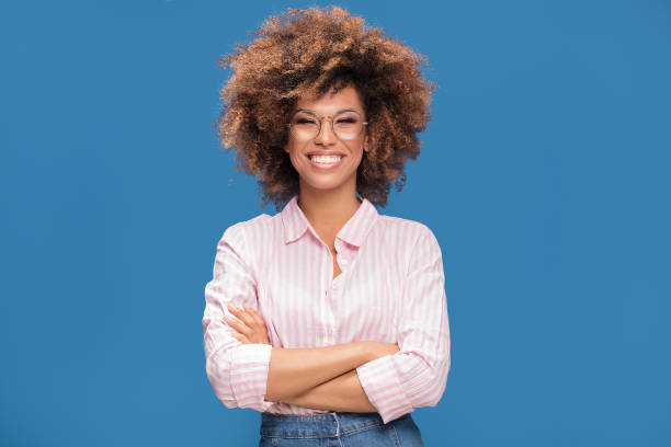 Portrait of afro girl in eyeglasses. Closeup portrait of Afro American woman with bushy hair wearing fashionable eyeglasses ,looking at camera and smiling, blue background. natural black hair photos stock pictures, royalty-free photos & images