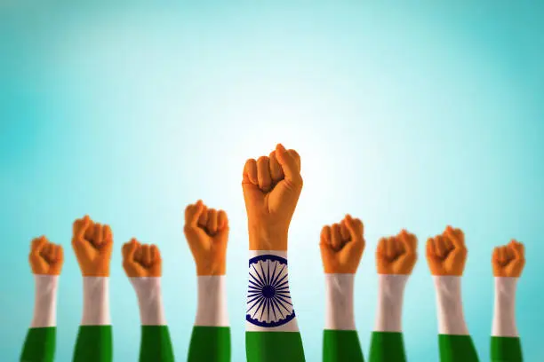 Photo of India national flag pattern on leader's fist isolated (clipping path) on blue mint sky for Human equal rights, labor day concept