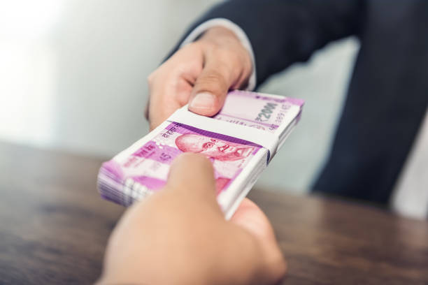 businessman giving money, indian rupee currency, to his partner - money roll fotos imagens e fotografias de stock