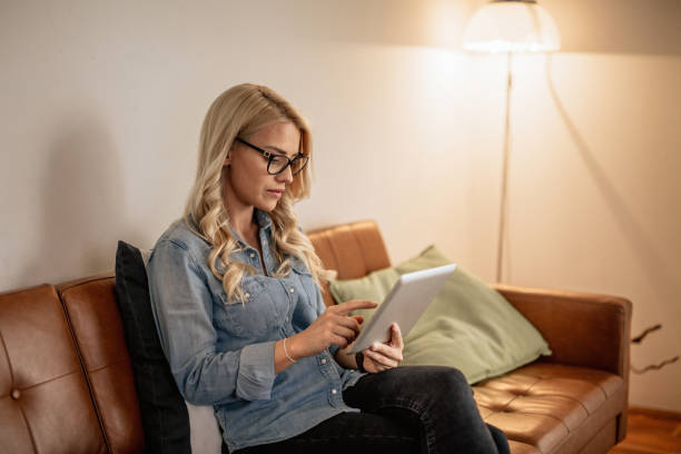 istock Woman using her tablet in the living room 995784490