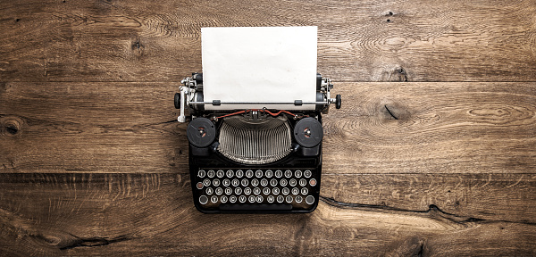 Antique typewriter with grungy textured paper page on rustic wooden background