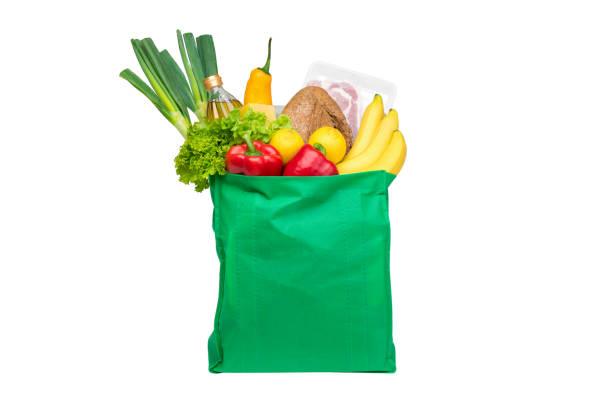 Food and groceries in green eco-friendly reusable shopping bag Food and groceries in green eco-friendly reusable shopping bag, isolated on white background reusable bag stock pictures, royalty-free photos & images