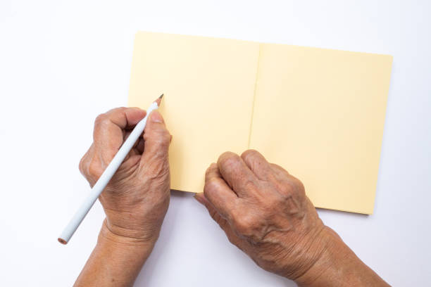 senior woman's left hand with white pencil writing on notebook isolated on white background, stationery concept - copy space left imagens e fotografias de stock