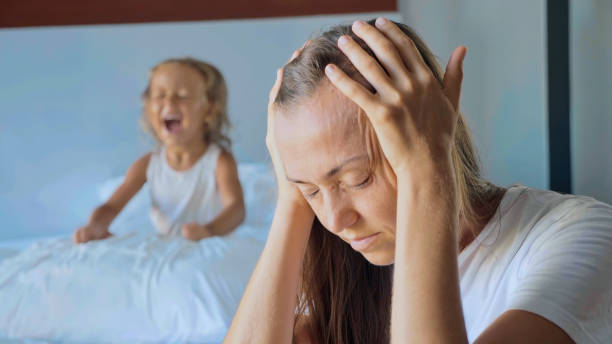 Upset mother with angry little child screaming pillow on the background stock photo