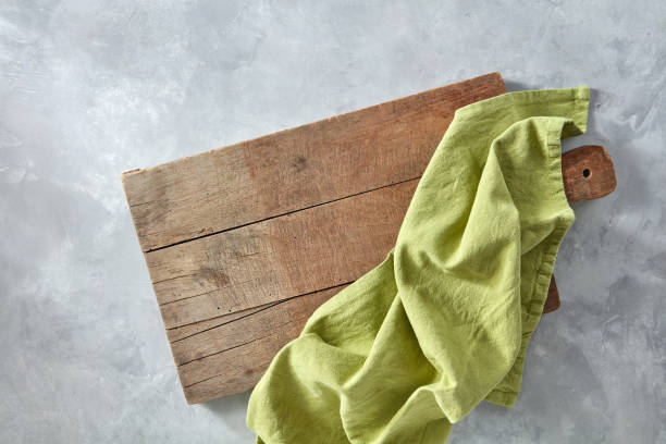 una tabla de madera con una servilleta de cocina verde sobre un fondo gris de hormigón con un espacio de la copia. vista superior - kitchen cloth fotografías e imágenes de stock