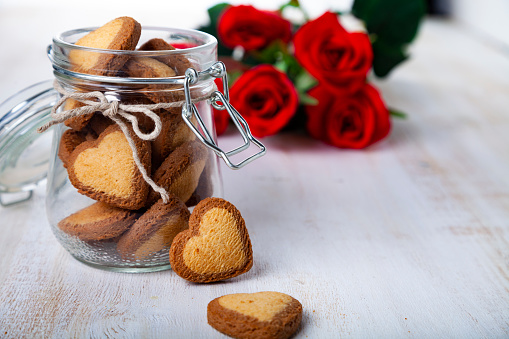 Heart-shaped cookies in a glass jar and red rose on St. Valentine's Day.