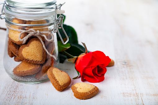 Heart-shaped cookies in a glass jar and red rose on St. Valentine's Day.