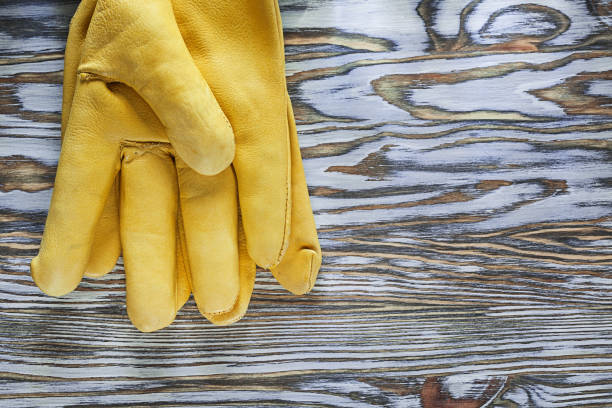 istock Yellow leather protective gloves on wooden board 995929056