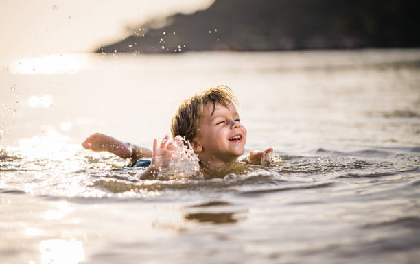 istock Playful boy having fun in shallow water during summer day at sea. 995932482