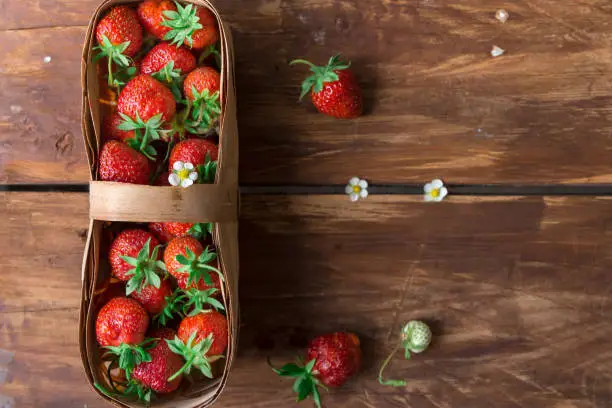 The top view fresh strawberry in a basket on a wooden rustic table. Copy space