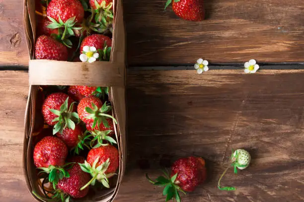 The top view fresh strawberry in a basket on a wooden table. Copy space