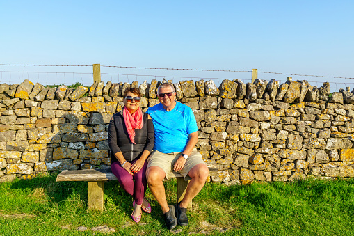 Senior couple sitting on bench in Welsh countryside